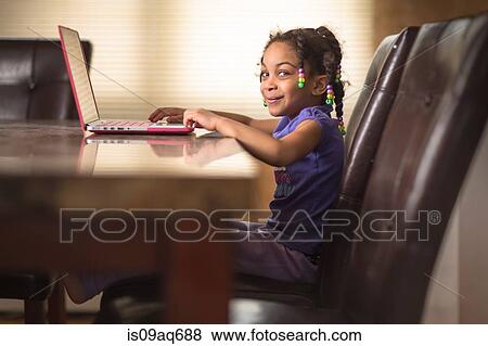 Portrait of cute girl at dining table using laptop View Large Photo Image Stock Photo - Portrait of cute girl at dining table using laptop. Fotosearch