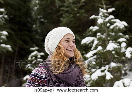 Stock Photo - Portrait of laughing young woman in front of snow covered fir trees. Fotosearch