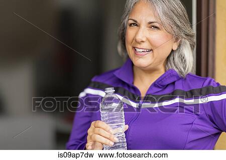 Stock Photo - Portrait of mature woman holding water bottle. Fotosearch