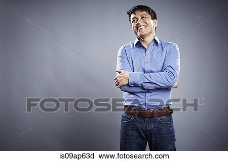 Stock Image - "Portrait of mid adult man, arms crossed, smiling". Fotosearch