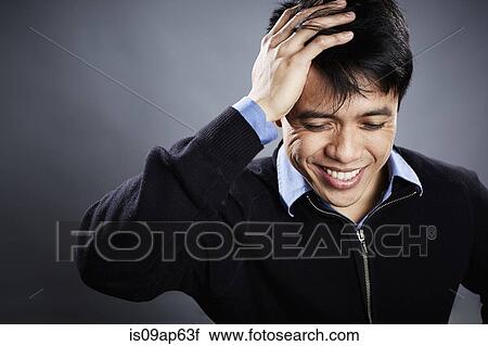 Stock Image - Portrait of mid adult man touching head. Fotosearch