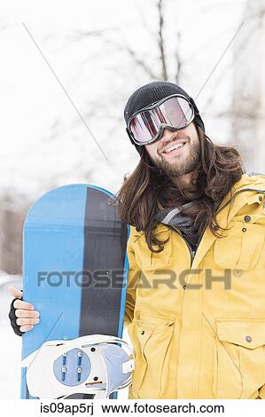 Portrait of smiling young man holding snowboard on street View Large Photo Image Stock Image - Portrait of smiling young man holding snowboard on street. Fotosearch