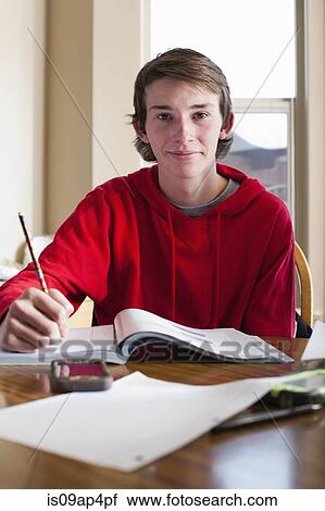 Portrait of teenage boy doing homework at dining room table View Large Photo Image Stock Image - Portrait of teenage boy doing homework at dining room table. Fotosearch