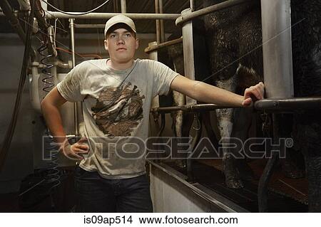 Portrait of teenage boy leaning on railing in dairy farm milking shed View Large Photo Image Picture - Portrait of teenage boy leaning on railing in dairy farm milking shed. Fotosearch