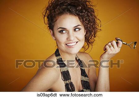 "Portrait of woman wearing beaded necklace, holding eyelash curler" View Large Photo Image Stock Photograph - "Portrait of woman wearing beaded necklace, holding eyelash curler". Fotosearch