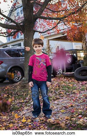 "Portrait of young boy, standing in garden surrounded by autumn leaves" View Large Photo Image Picture - "Portrait of young boy, standing in garden surrounded by autumn leaves". Fotosearch