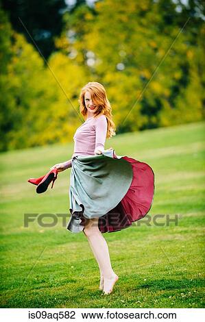 Portrait of young female dancer poised holding skirt and red high heels in park View Large Photo Image Stock Image - Portrait of young female dancer poised holding skirt and red high heels in park. Fotosearch