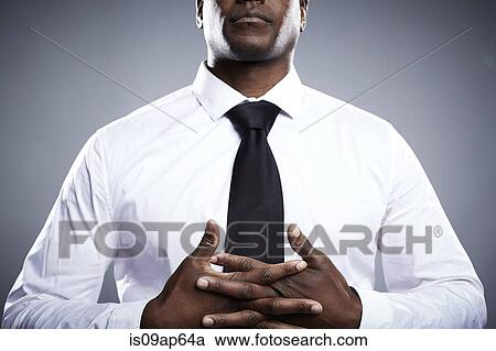Stock Image - "Portrait of young man, hands clasped, mid section". Fotosearch
