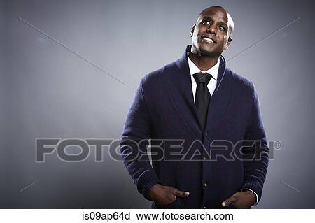 Stock Image - "Portrait of young man, hands in pockets, looking up". Fotosearch