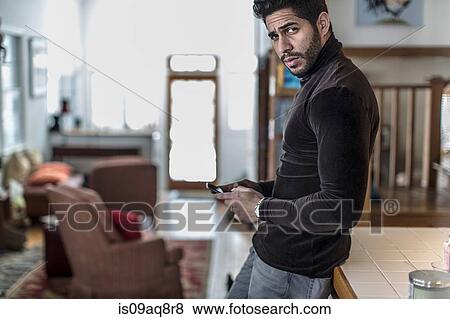 Stock Photo - Portrait of young man holding cell phone. Fotosearch