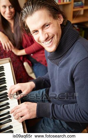 Stock Photography - Portrait of young man playing the piano for girlfriend. Fotosearch