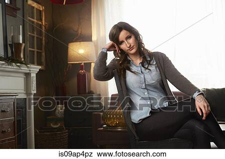 Stock Photo - Portrait of young woman leaning back on living room chair. Fotosearch