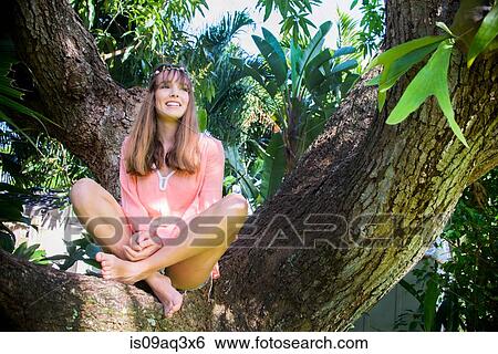 Portrait of young woman looking out from tree View Large Photo Image Stock Photograph - Portrait of young woman looking out from tree. Fotosearch