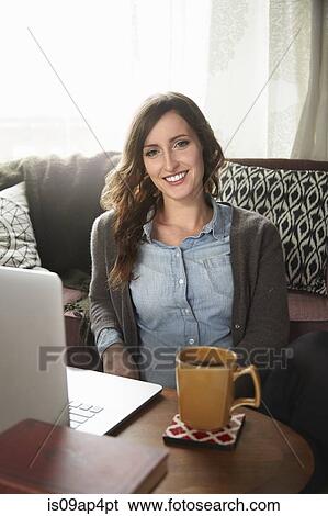 Portrait of young woman sitting on floor drinking coffee and using laptop View Large Photo Image Stock Photograph - Portrait of young woman sitting on floor drinking coffee and using laptop. Fotosearch