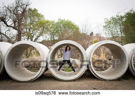 Portrait of young woman standing inside concrete pipe in rural landscape View Large Photo Image Stock Photo - Portrait of young woman standing inside concrete pipe in rural landscape. Fotosearch
