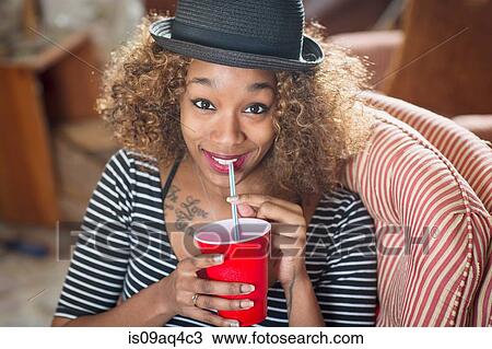 Portrait of young woman wearing fedora and drinking soft drink View Large Photo Image Stock Image - Portrait of young woman wearing fedora and drinking soft drink. Fotosearch