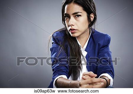 Stock Photo - Portrait of young woman with hands clasped and serious expression. Fotosearch
