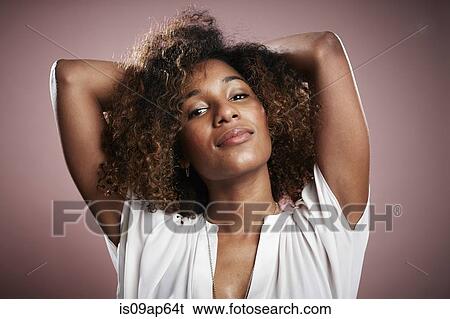 Stock Photograph - Portrait of young woman with hands behind head. Fotosearch