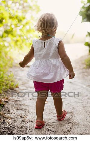 Stock Photograph - "Rear view of female toddler toddling on woodland beach path, Anna Maria Island, Florida, USA". Fotosearch