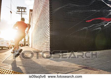 Rear view of male runner running on sidewalk View Large Photo Image Stock Photograph - Rear view of male runner running on sidewalk. Fotosearch