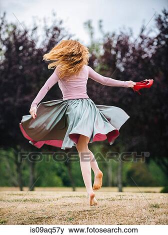 Rear view of young woman dancing and twirling and in park View Large Photo Image Stock Photo - Rear view of young woman dancing and twirling and in park. Fotosearch