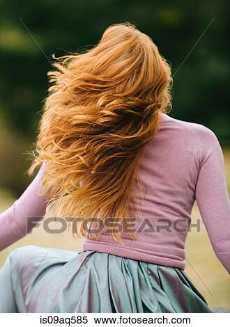 Rear view of young woman with long red hair twirling in park View Large Photo Image Stock Photography - Rear view of young woman with long red hair twirling in park. Fotosearch
