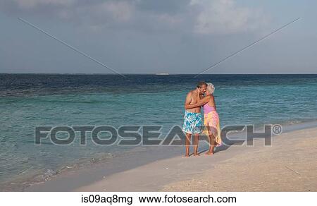 Stock Image - "Senior couple hugging on beach, Maldives". Fotosearch