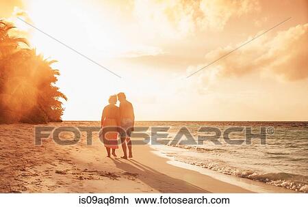 Stock Image - "Senior couple on beach at sunset, Maldives". Fotosearch
