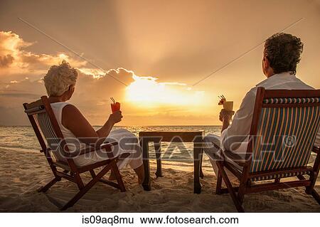 "Senior couple with drinks on beach, Maldives" View Large Photo Image Stock Photograph - "Senior couple with drinks on beach, Maldives". Fotosearch
