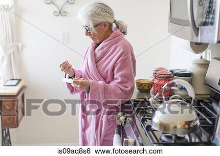 Senior woman standing in kitchen holding prescription drugs packet View Large Photo Image Stock Photograph - Senior woman standing in kitchen holding prescription drugs packet. Fotosearch