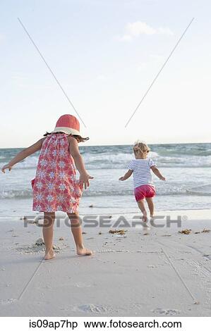 Siblings exploring on the beach at sunset View Large Photo Image Stock Photography - Siblings exploring on the beach at sunset. Fotosearch