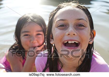 Stock Photography - Sisters playing in sea. Fotosearch