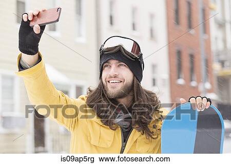 Smiling male snowboarder taking smartphone selfie in street View Large Photo Image Stock Image - Smiling male snowboarder taking smartphone selfie in street. Fotosearch