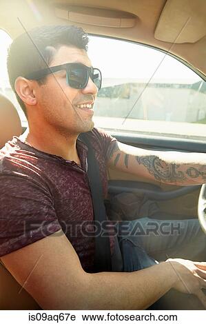 Stock Image - Smiling young man driving car. Fotosearch