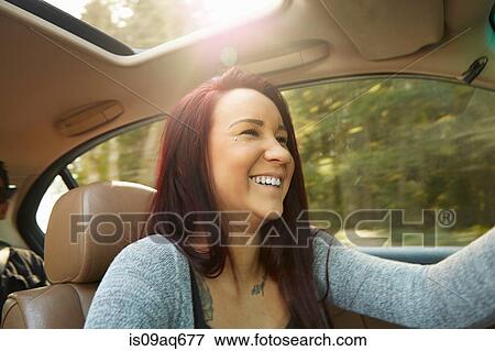 Stock Photo - Smiling young woman driving car. Fotosearch