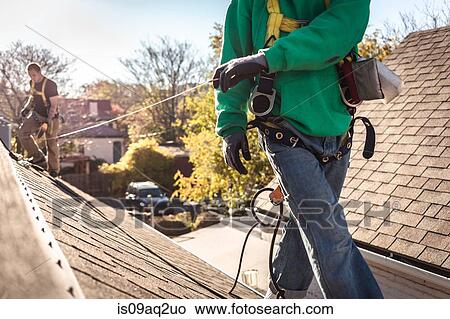 Picture - Solar panel installation crew on roof of house. Fotosearch