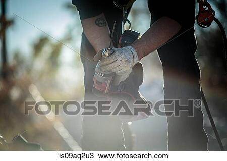 Stock Image - Solar panel installation worker with drill. Fotosearch
