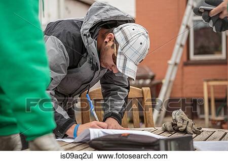 Stock Image - Solar panel installation worker writing paperwork. Fotosearch