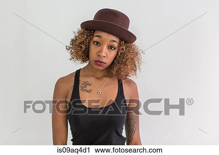 Stock Image - Studio portrait of young woman wearing felt hat. Fotosearch