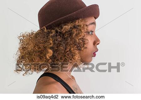 Stock Image - Studio profile portrait of young woman wearing felt hat. Fotosearch