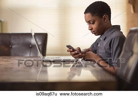 Teenage boy at dining table reading smartphone texts View Large Photo Image Stock Photograph - Teenage boy at dining table reading smartphone texts. Fotosearch