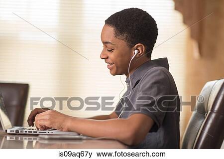 Teenage boy at dining table typing on laptop View Large Photo Image Stock Photo - Teenage boy at dining table typing on laptop. Fotosearch