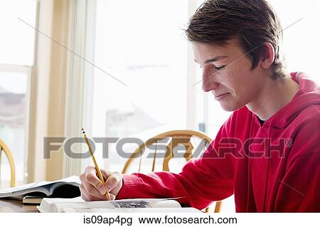 Teenage boy doing homework at dining room table View Large Photo Image Stock Image - Teenage boy doing homework at dining room table. Fotosearch
