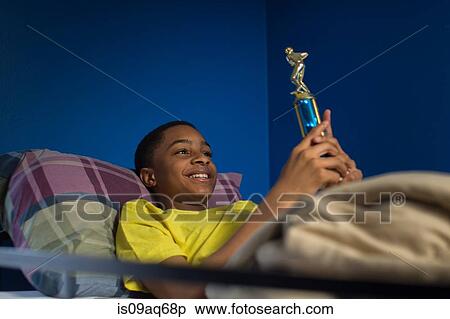 Teenage boy lying in bunkbed admiring trophy View Large Photo Image Stock Photography - Teenage boy lying in bunkbed admiring trophy. Fotosearch