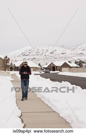 Teenage boy reading smartphone texts whilst walking path in snow covered village View Large Photo Image Stock Image - Teenage boy reading smartphone texts whilst walking path in snow covered village. Fotosearch