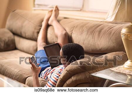 Teenage boy reclining on sofa reading smartphone text View Large Photo Image Stock Image - Teenage boy reclining on sofa reading smartphone text. Fotosearch