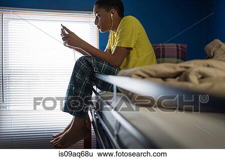 Teenage boy sitting on bunkbed reading smartphone texts View Large Photo Image Stock Photograph - Teenage boy sitting on bunkbed reading smartphone texts. Fotosearch