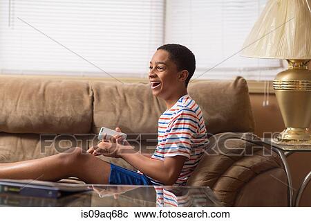 Teenage boy sitting up on sofa laughing View Large Photo Image Stock Image - Teenage boy sitting up on sofa laughing. Fotosearch