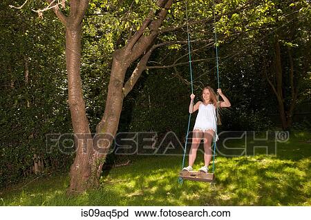 Teenage girl swinging on tree swing View Large Photo Image Stock Image - Teenage girl swinging on tree swing. Fotosearch