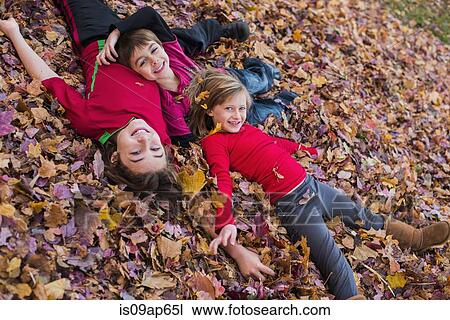 Three siblings lying in autumn leaves View Large Photo Image Stock Image - Three siblings lying in autumn leaves. Fotosearch